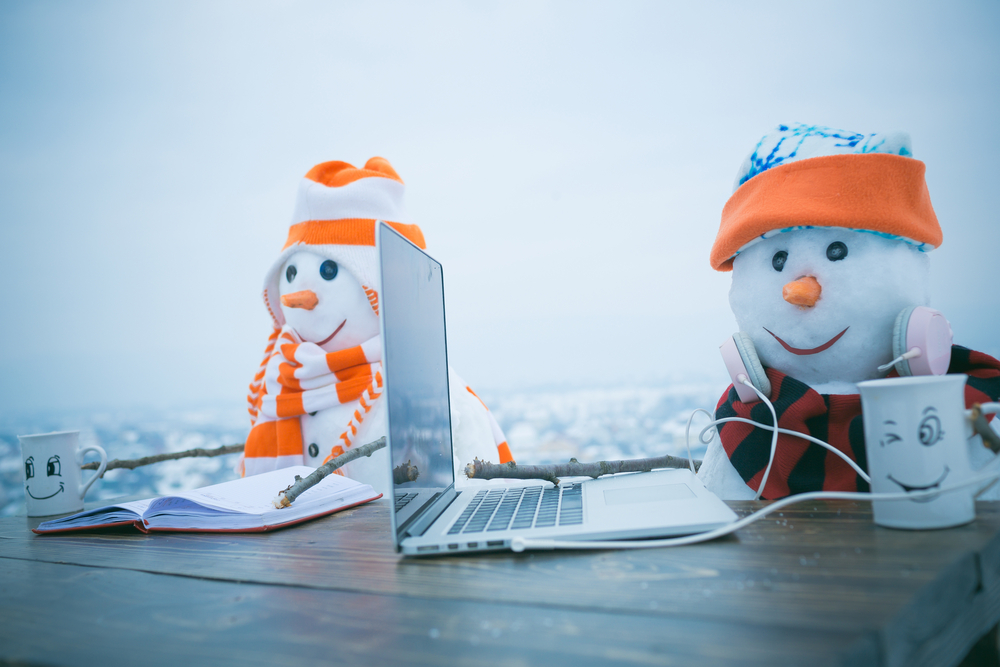 two snowmen, sitting, with laptop book and mugs on a video call with loved ones