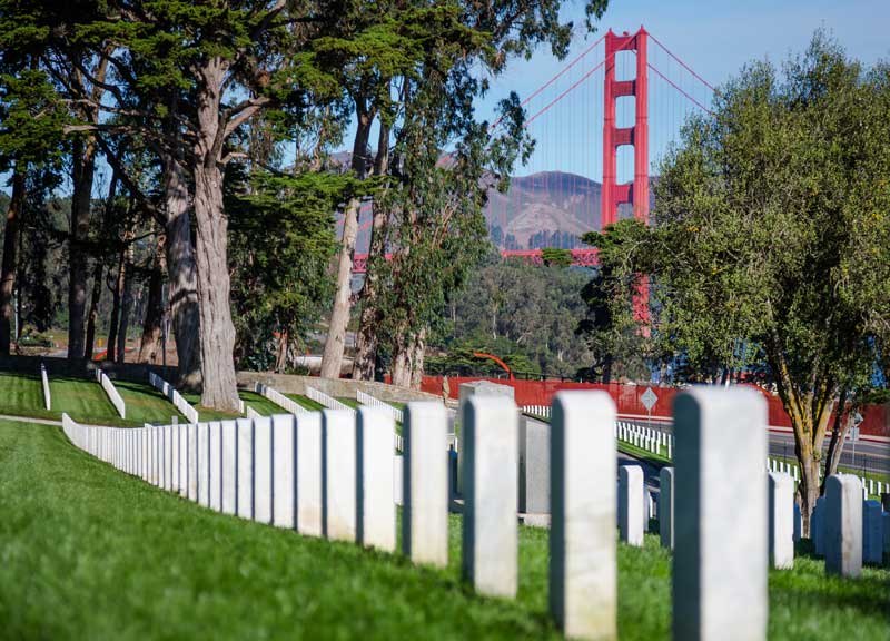 military cemetery in San Francisco with gravestones in the foreground and the Golden Gate Bridge in the background