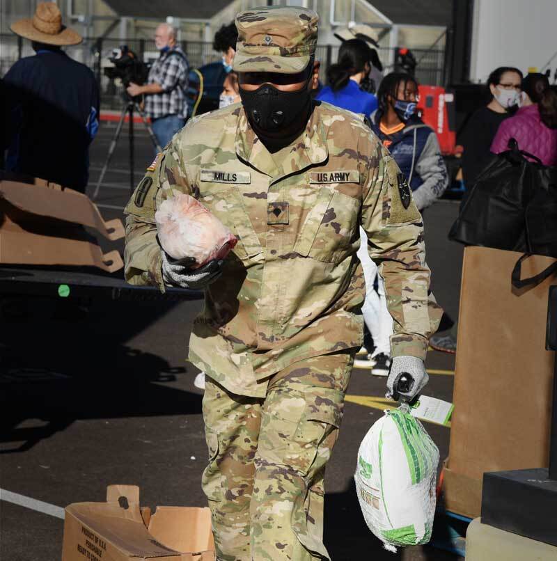 Service member, carrying turkeys, volunteering at food bank