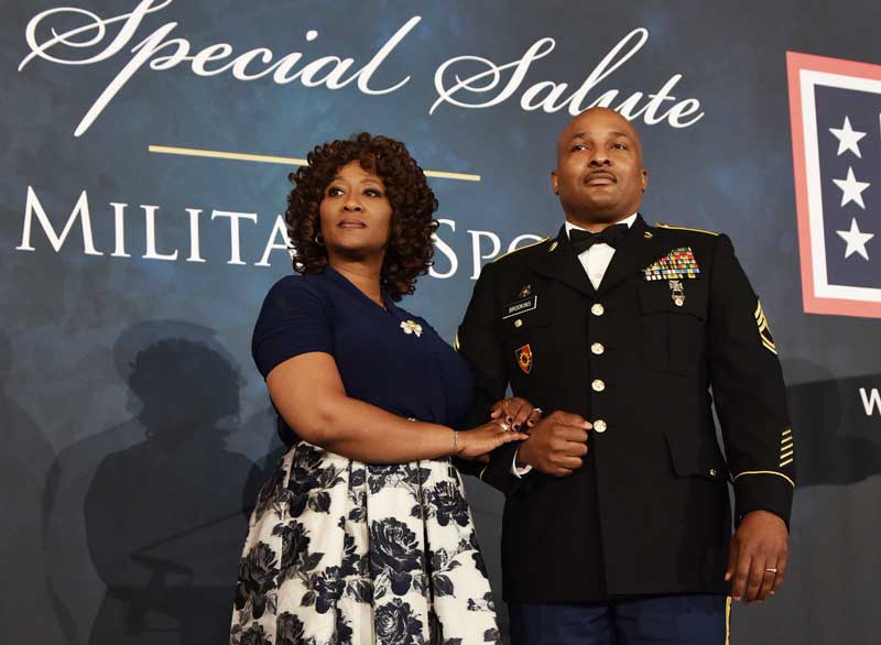 Army officer poses with his spouse at a military event
