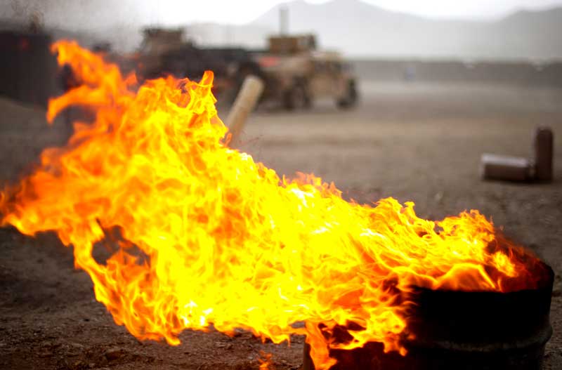 flame from burn pits burns near military vehicles