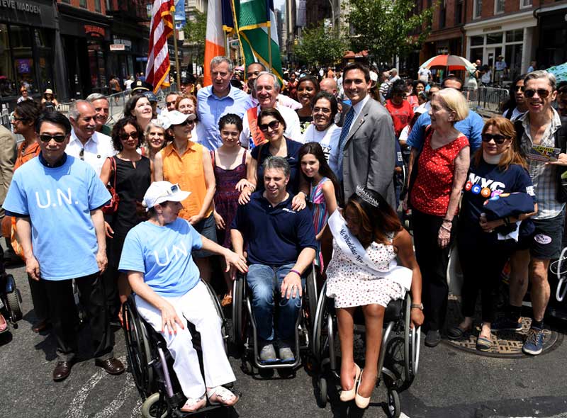 large diverse group of people, some with physical disabilities, smile at the camera
