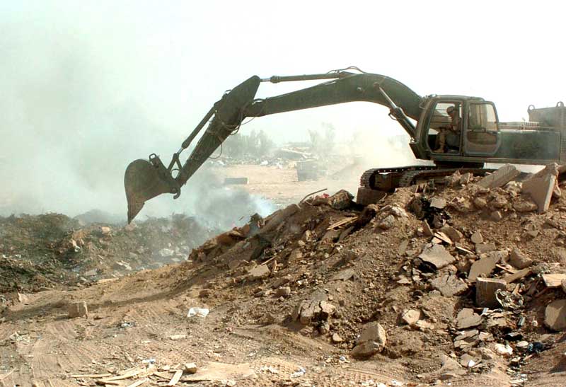 service member operates crane near smoking burn pit