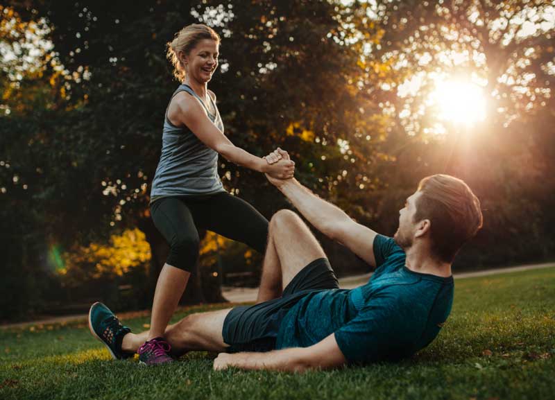 woman standing grasps hand of man on ground to help him up